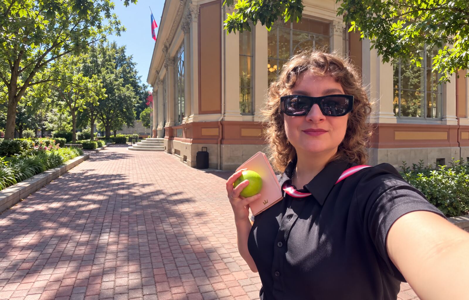 intervista-anna-kochkina-opposizione-russa — Anna Kochkina con una mela verde davanti a un edificio.